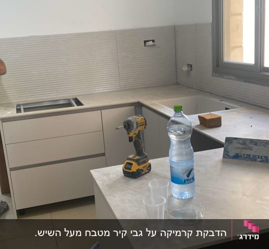 מטבח בשיפוץ עם כלי עבודה ובקבוק מים